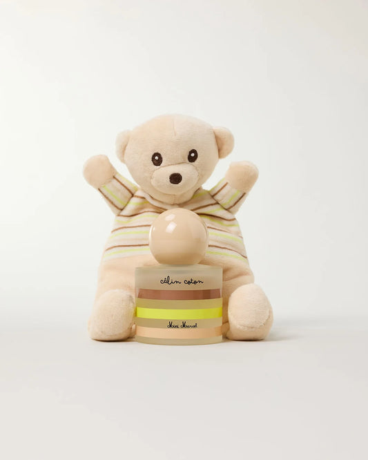 Flacon de Câlin Coton, parfum pour bébé entouré d'un doudou