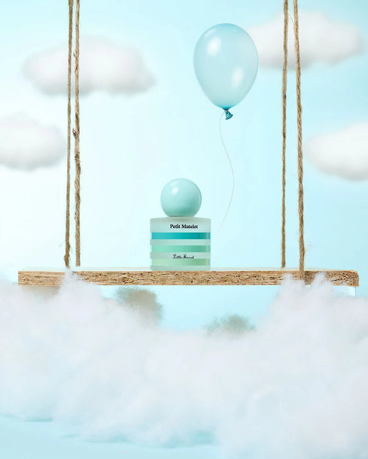 Flacon de notre parfum, Petit Matelot, sur une balançoire dans les nuages